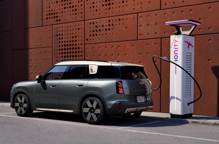 MINI Countryman Elettrica davanti a una stazione di ricarica IONITY MINI Countryman Elettrica vista di lato davanti a una stazione di ricarica IONITY